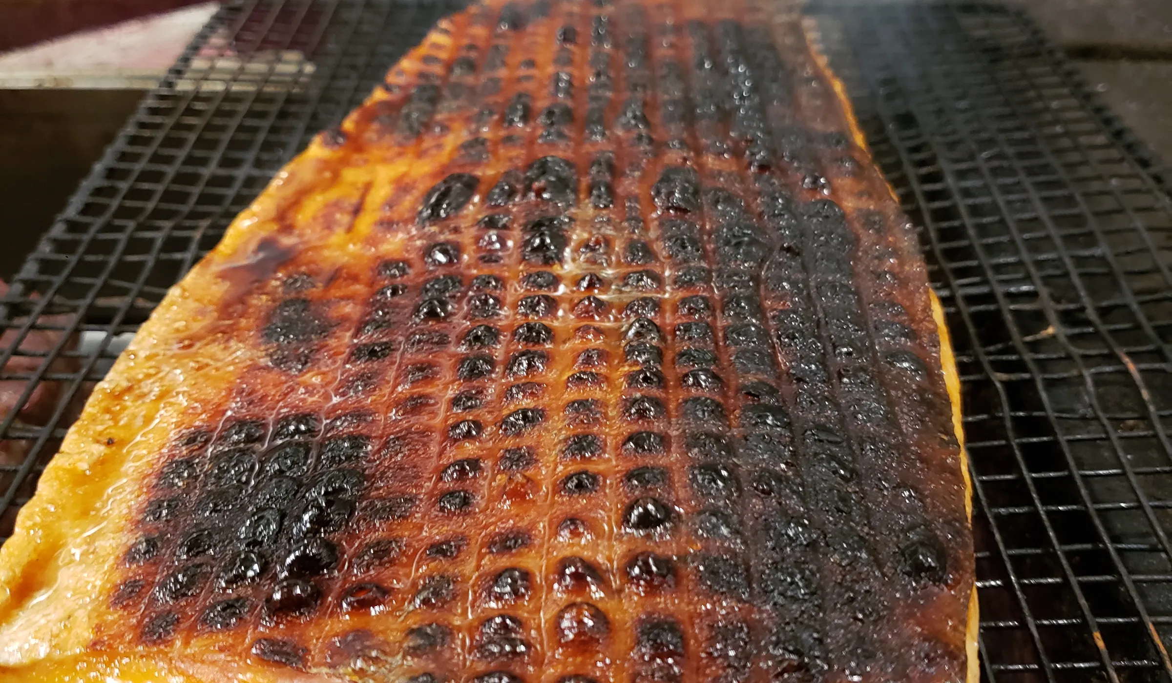 Salmon grilling over open flame, skin crisping
