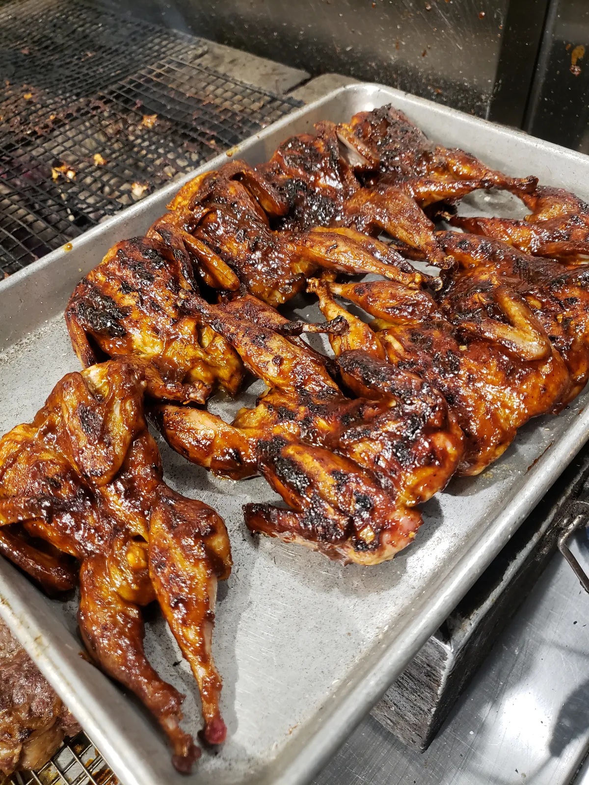 A sheet tray of glazed grilled chicken, fresh off the grill