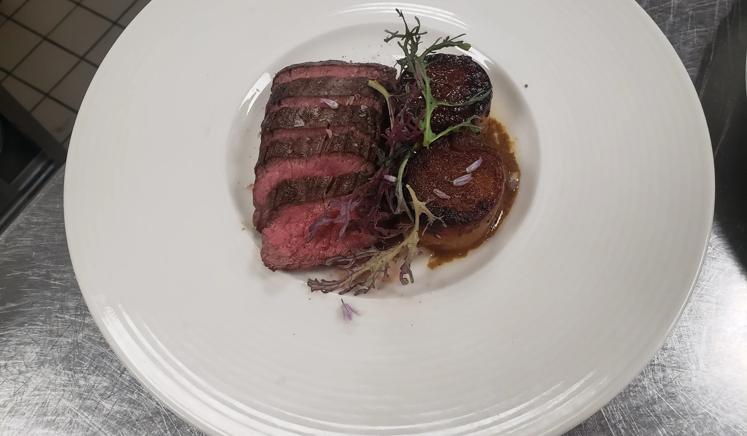 Sliced steak and layered potatoes with shaved truffle, plated by Kyle